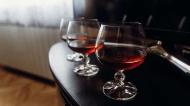 Expensive glasses with whiskey on dark wooden table closeup