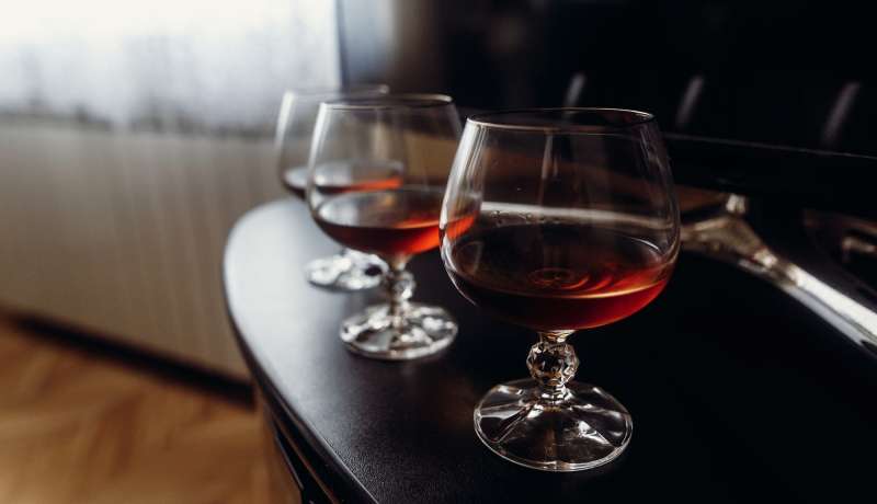 Expensive glasses with whiskey on dark wooden table closeup